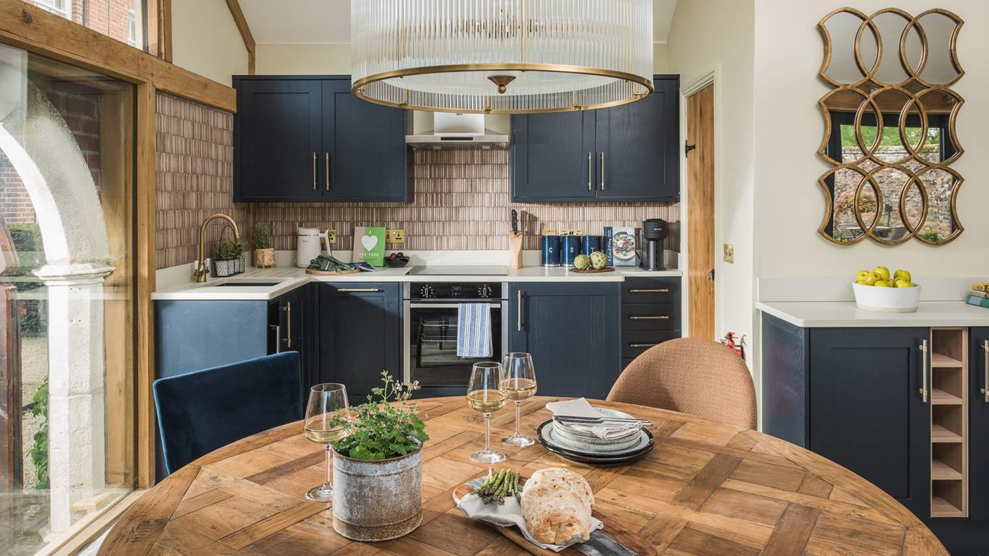 Exposed wood beams, deep blue units and brass inflections add tone and depth to this breath-taking space