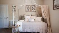 Calling for restful days you'll find a canopy bed with an elegant, exposed frame topped with a medley of cushions and throws