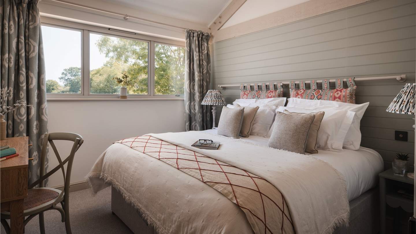 The second bedroom is simply a dream in calming neutral shades, with touches of sage green and a sweet Aztec headboard above the super king zip-and-link bed