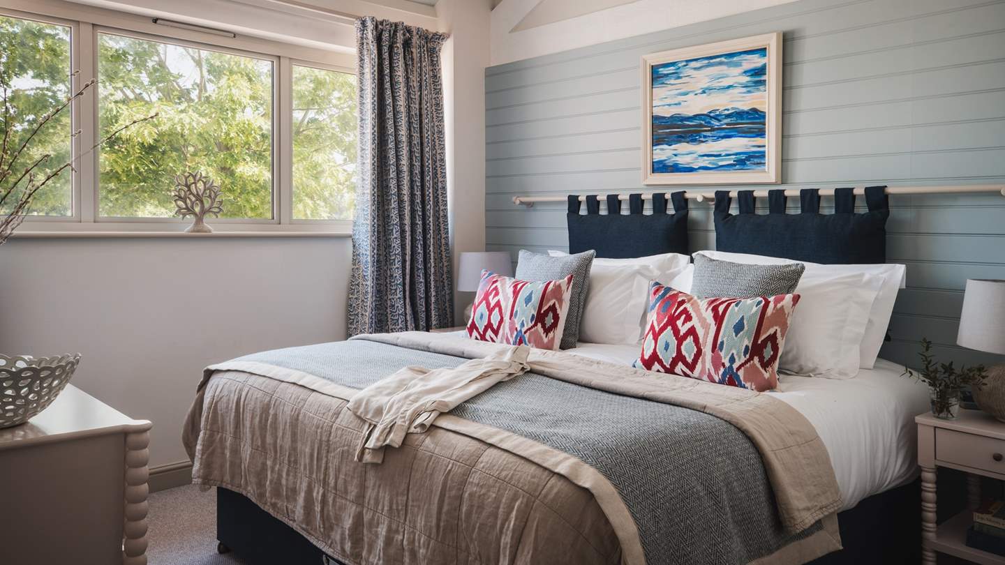 The master bedroom is dressed in soft blue shades, with a vaulted ceiling and a super king zip-and-link bed taking centre stage