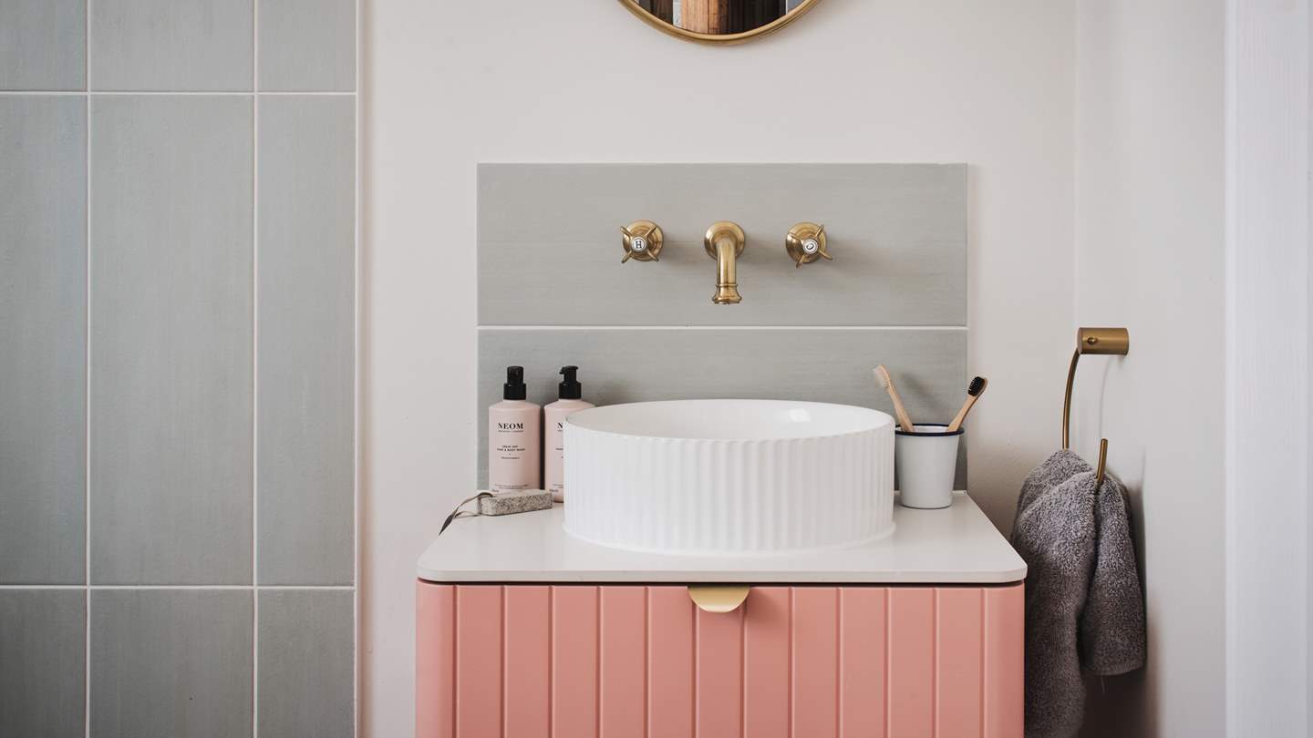 We love the gorgeous brass detailing and pretty pink bathroom units in the shower room