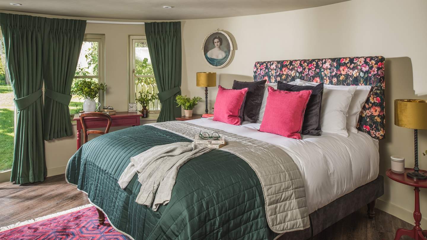 The king size bed, featuring a beautiful floral headboard, beckons for restful repose, whilst French doors open out to the luscious garden