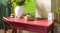 Gorgeous berry-hued bedside and dressing tables add a pop of colour to this charming space