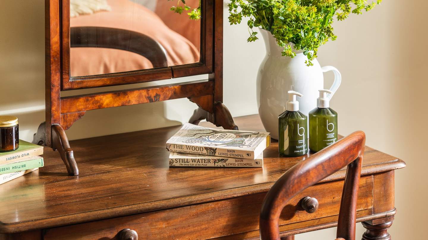 A sleek, vintage dressing table and stunning window-style mirror draw the eye around the room
