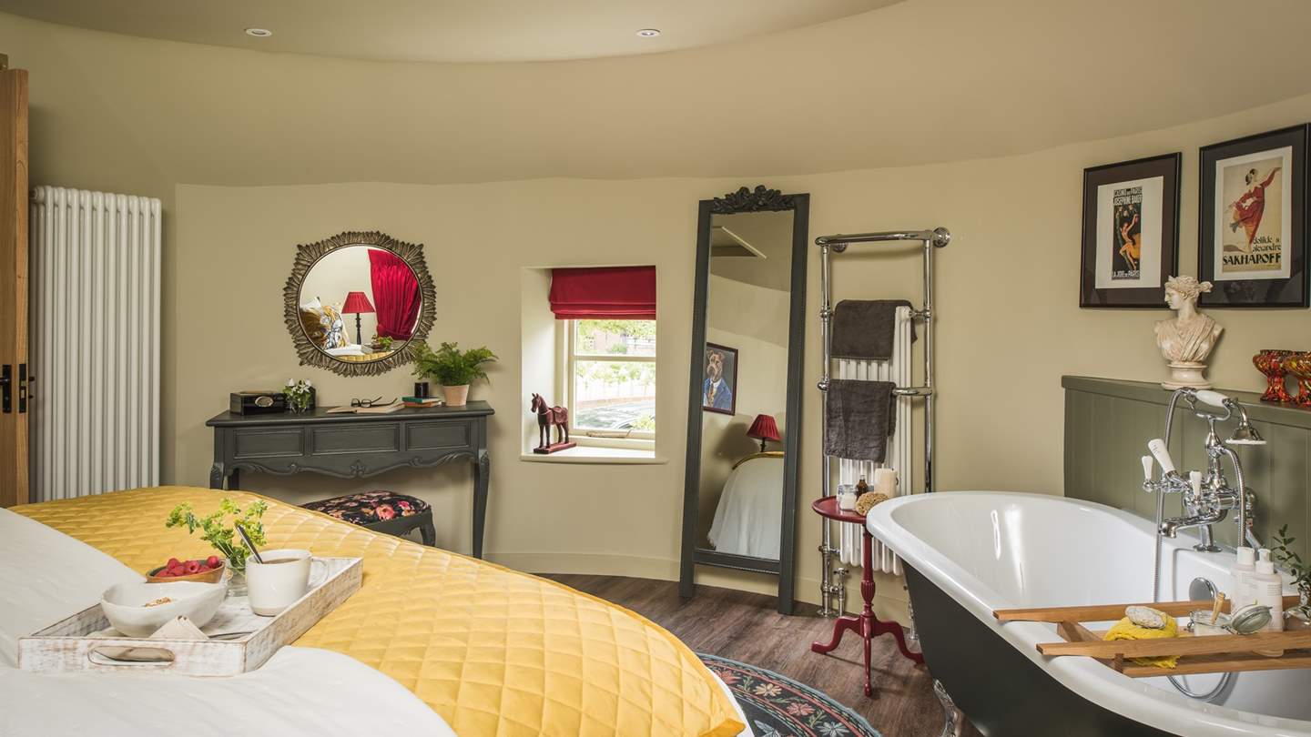Warmth wraps around the circular master bedroom, through natural toned walls and the arresting hue of the deep green freestanding roll top bath