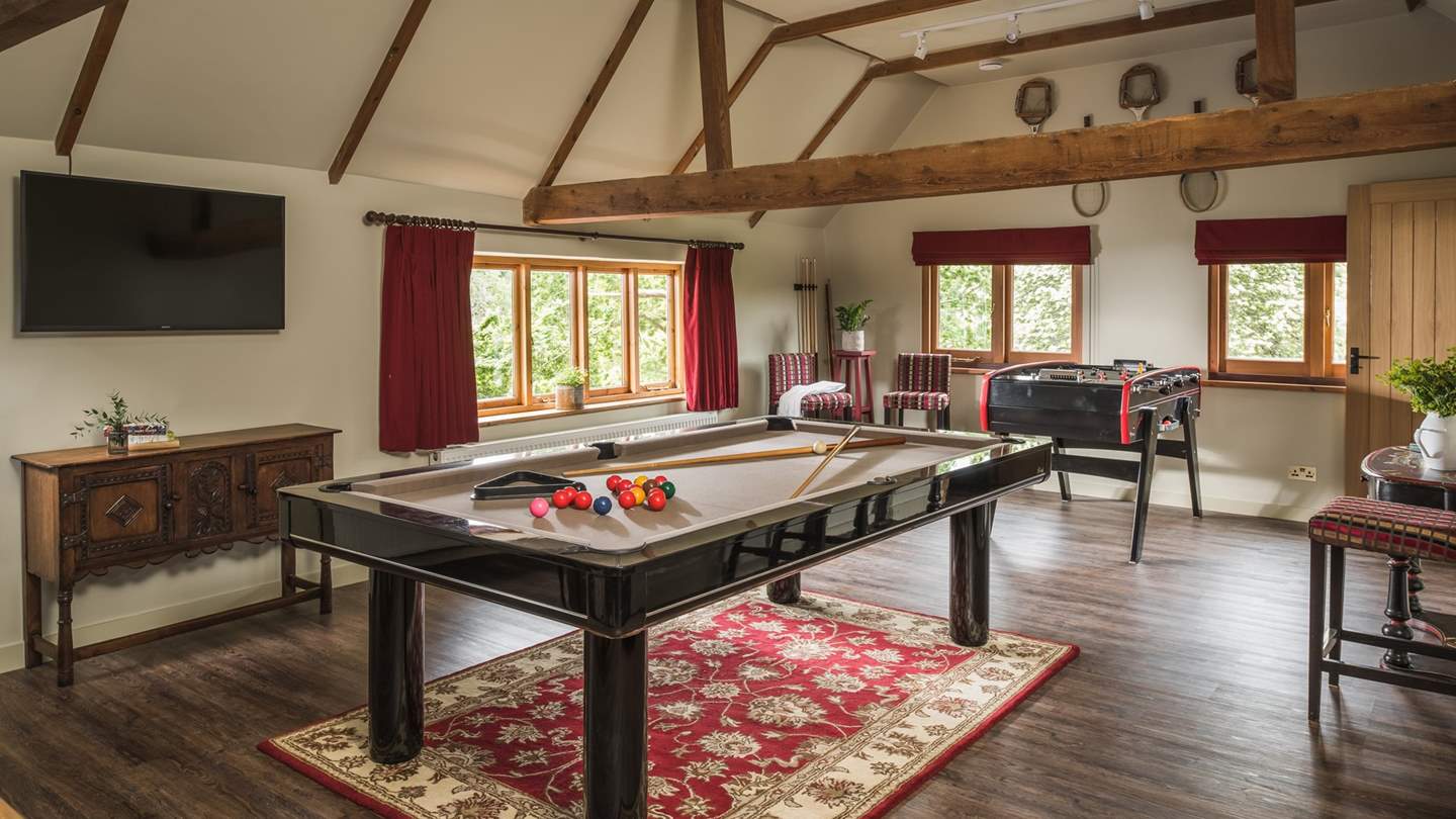 Promising hours of fun with a pool table, retro style football table, and another wall-mounted TV