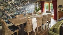 A handsome wooden dining table, which was made at a local forge and boasts ten Cox & Cox wicker chairs, sits behind the living area