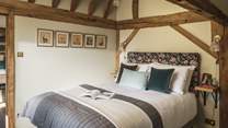 Bedroom five features traditional exposed beams and sumptuous earth tones across the king size bed