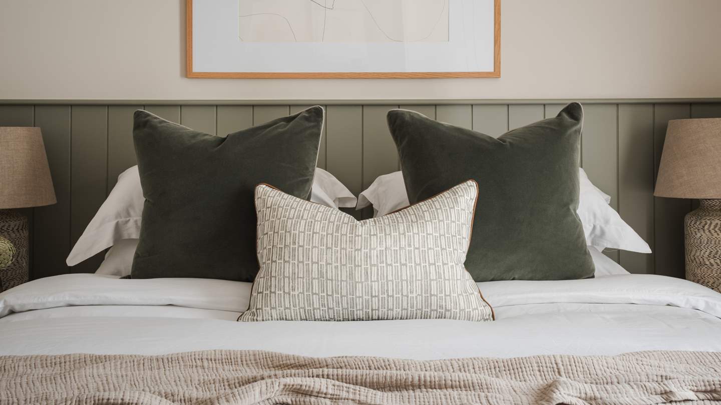The bedroom features organic tones and forest-hued wood panelling