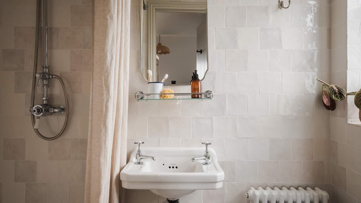 Just next door, an en suite adorned with Zellige-style tiling offers a spacious walk-in shower with a rainfall head