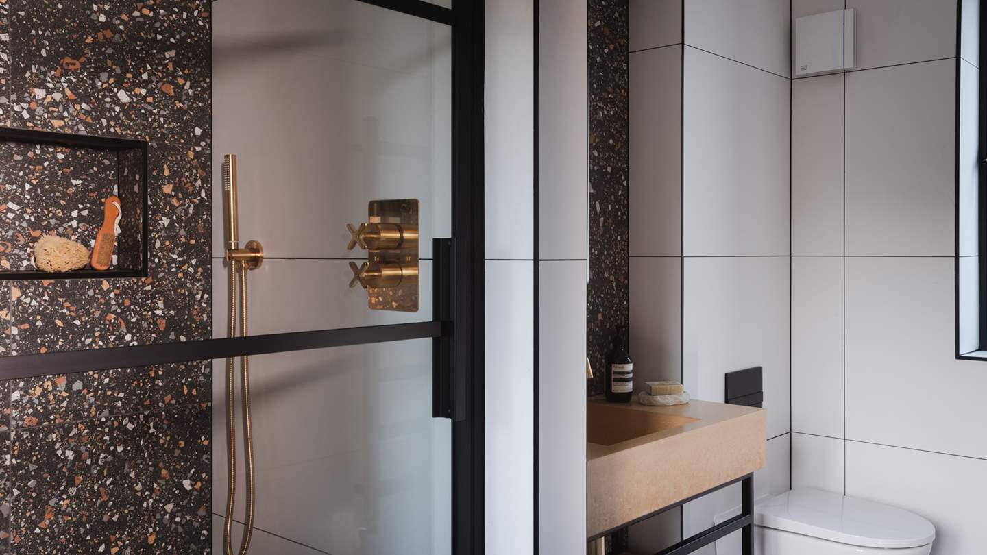 Just next door is the downstairs shower room, where you'll find gilded accents and gorgeous terrazzo tiling 