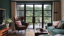 Overlooking the surrounding woodland through Crittall-style glass doors is the adjoining living space