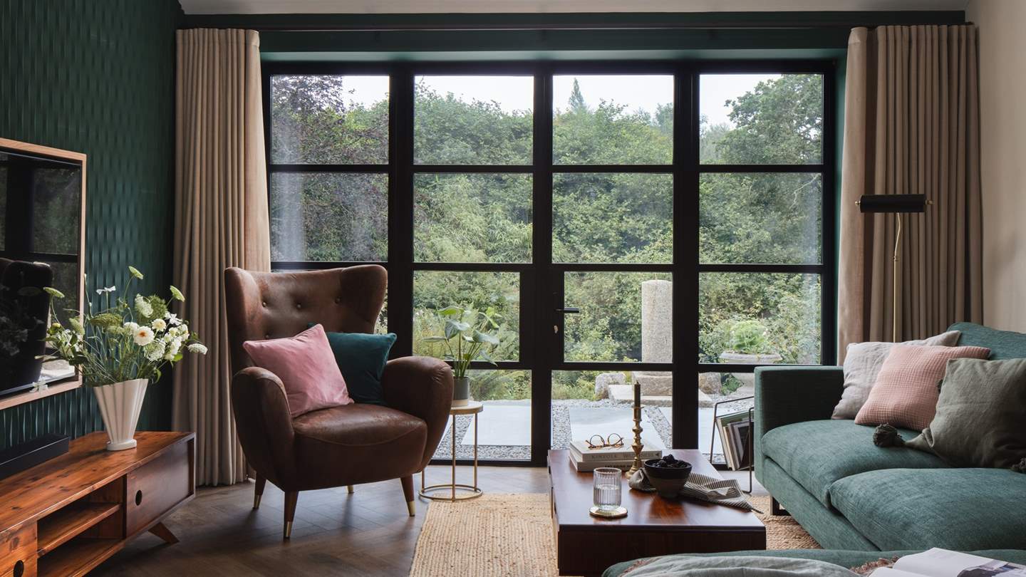 Overlooking the surrounding woodland through Crittall-style glass doors is the adjoining living space