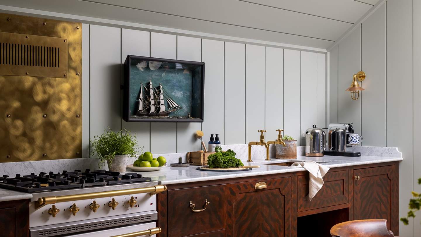 Glossy marble worktops and brass detailing pair beautifully with the rich mahogany kitchen cupboards