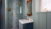 Next door, you will find the shower room in soft teal hues with brass detailing