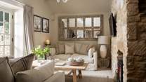 Two linen sofas and luxurious, soft furnishings in muted tones beautifully complement the exposed stonework