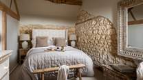 Soothing neutral tones, exposed Cotswold stonework and rustic beams continue into the bedroom, complete with a king size bed 