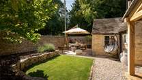 The Honeypot's garden promises a tranquil space with manicured greenery, a paved patio, and verdant lawn