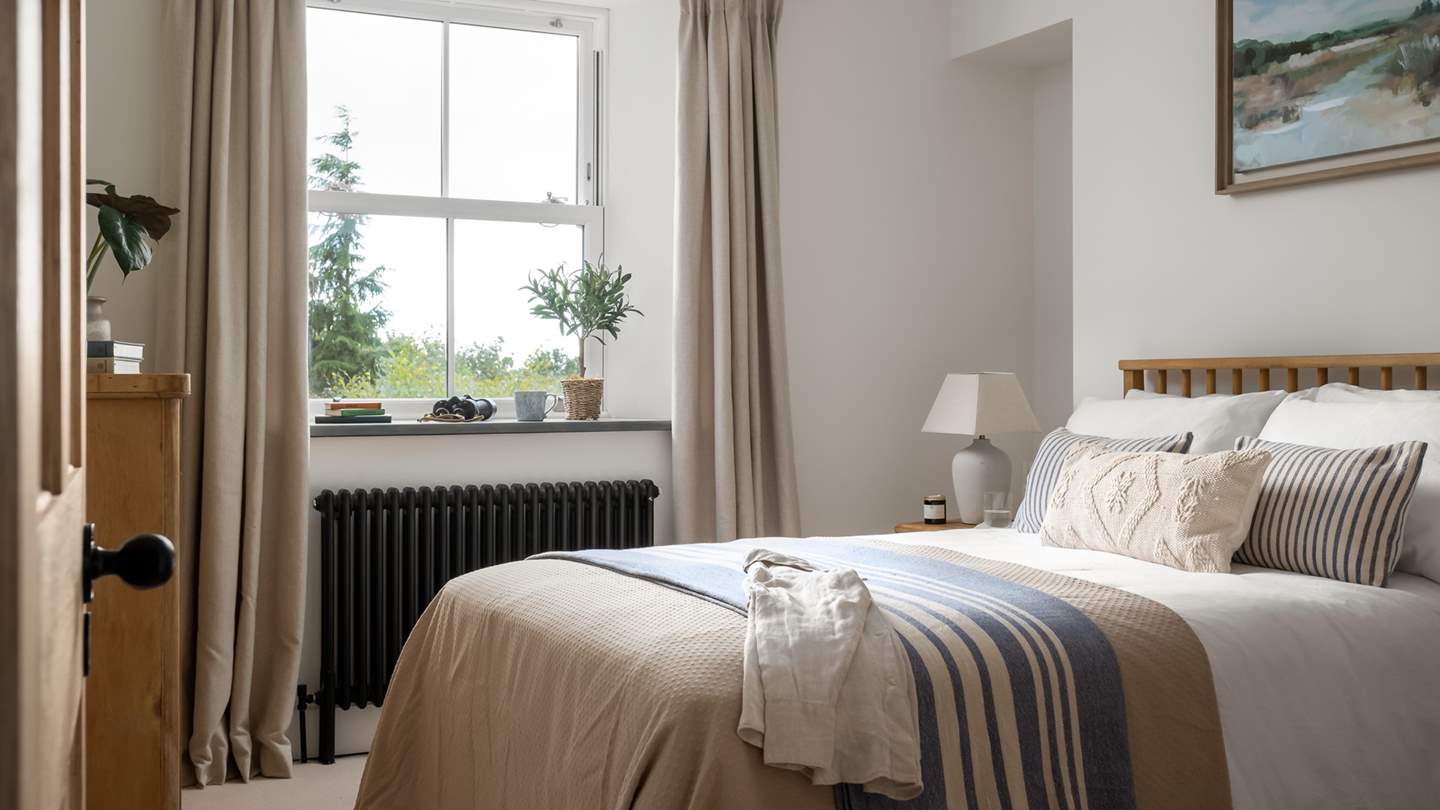 Warm neutrals flow through the first bedroom, crafting a serene space in which to unwind