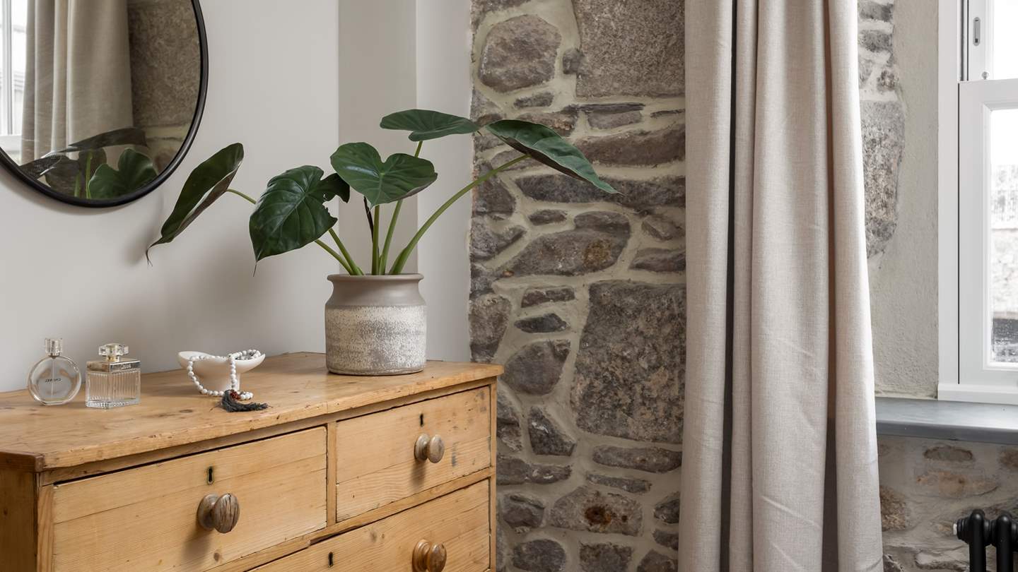 A gorgeous, exposed, stone wall frames the sun-soaked window 