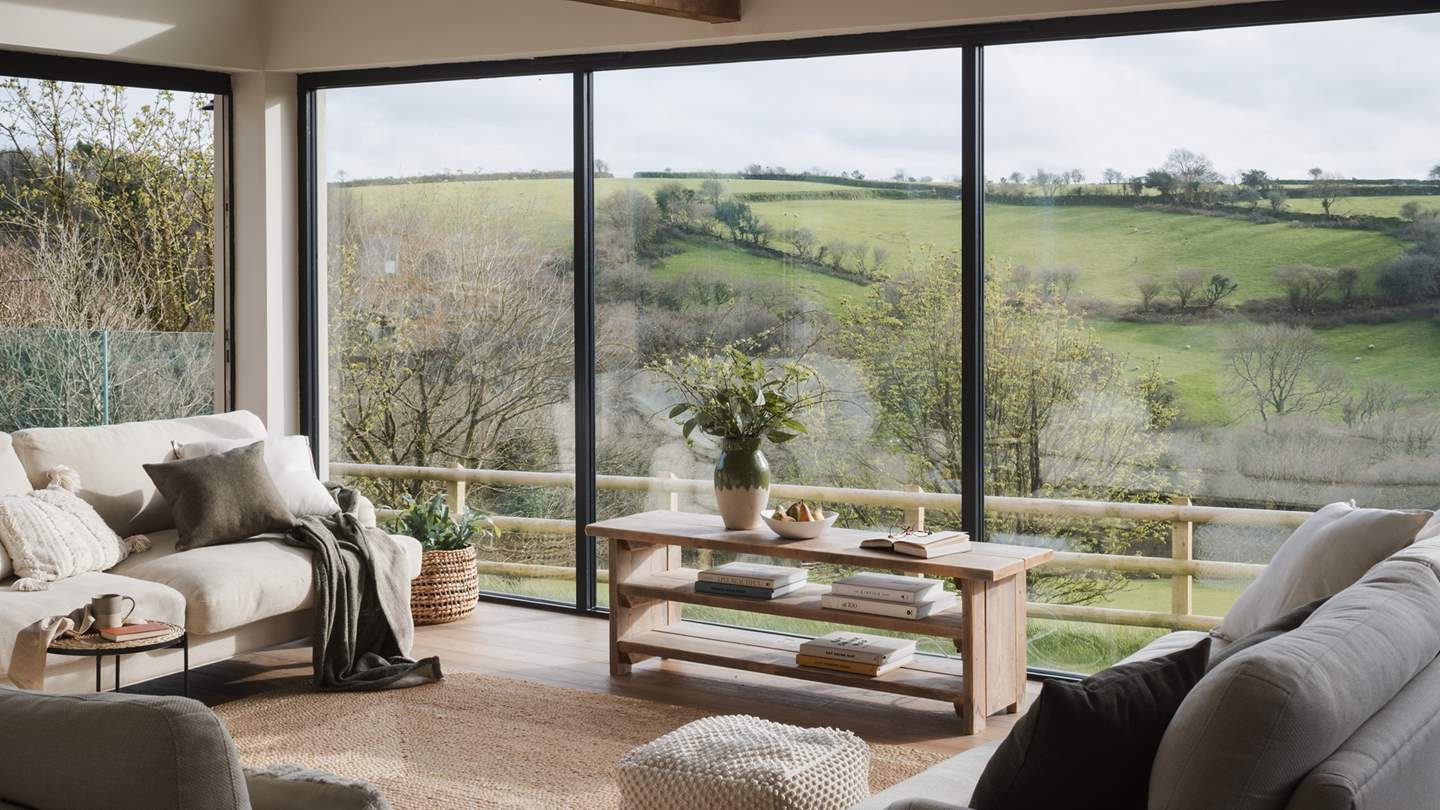 As soon as you step into the living room, your eyes drift to the incredible floor to ceiling windows that look out across a patchwork of Cornish fields