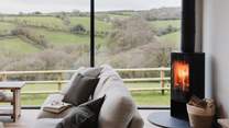 A flickering wood burning stove sits in the corner casting a rosy glow over the room
