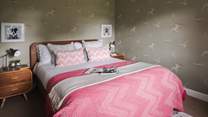 Bedroom two has a comfortable king size bed dressed in vibrant cushions and throws