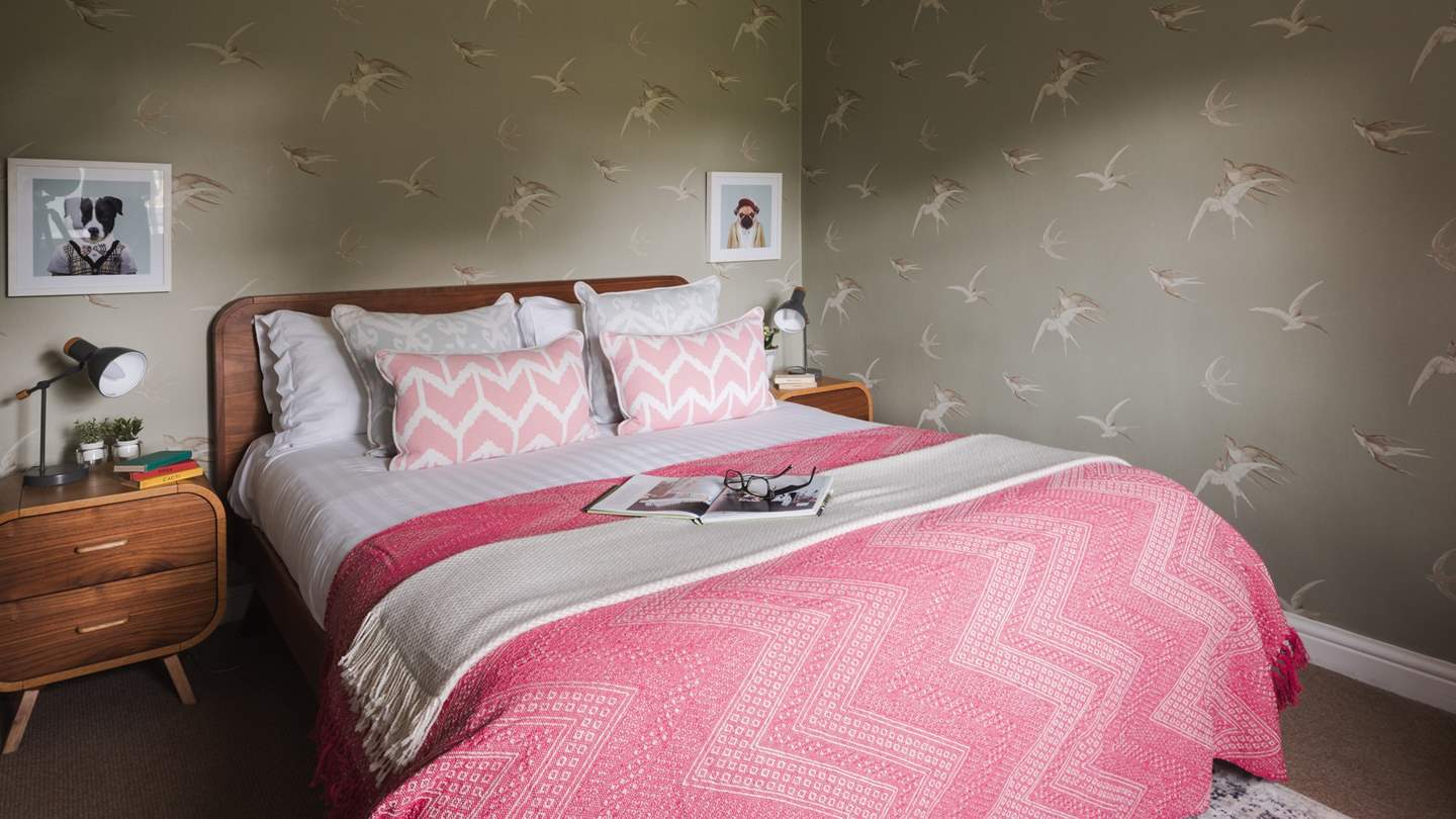 Bedroom two has a comfortable king size bed dressed in vibrant cushions and throws