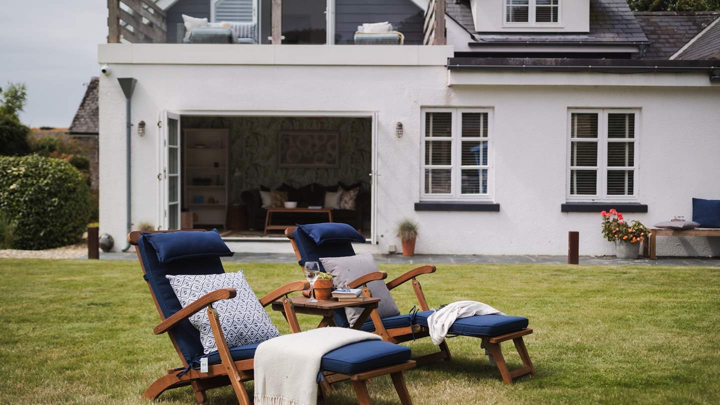 Flowing from large patio doors from the lounge, a large, manicured garden rolls towards a fenced boundary, beyond which countryside scenes 