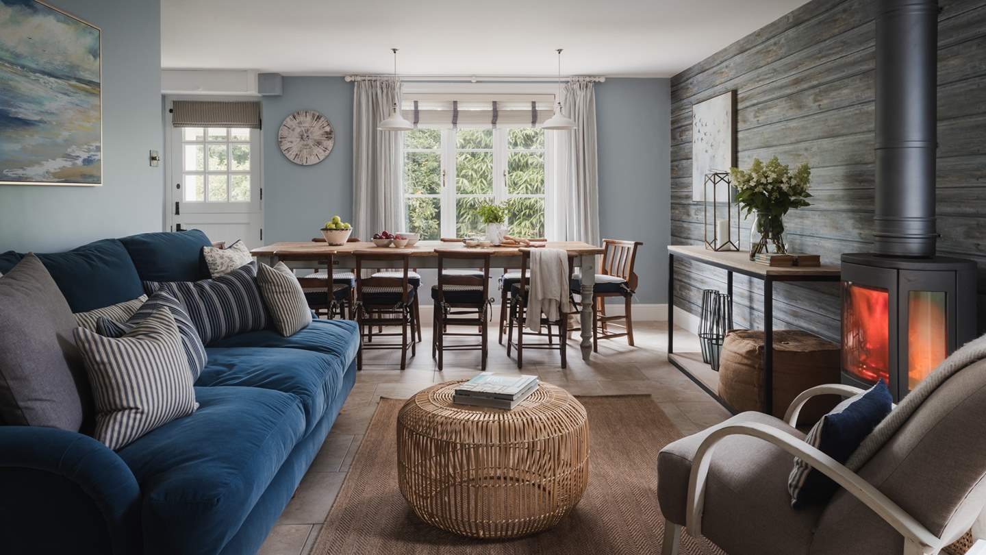 Bridging the space between the kitchen and dining area, the beautiful snug with a richly cosy navy sofa and comfortable armchair calls for relaxed moments
