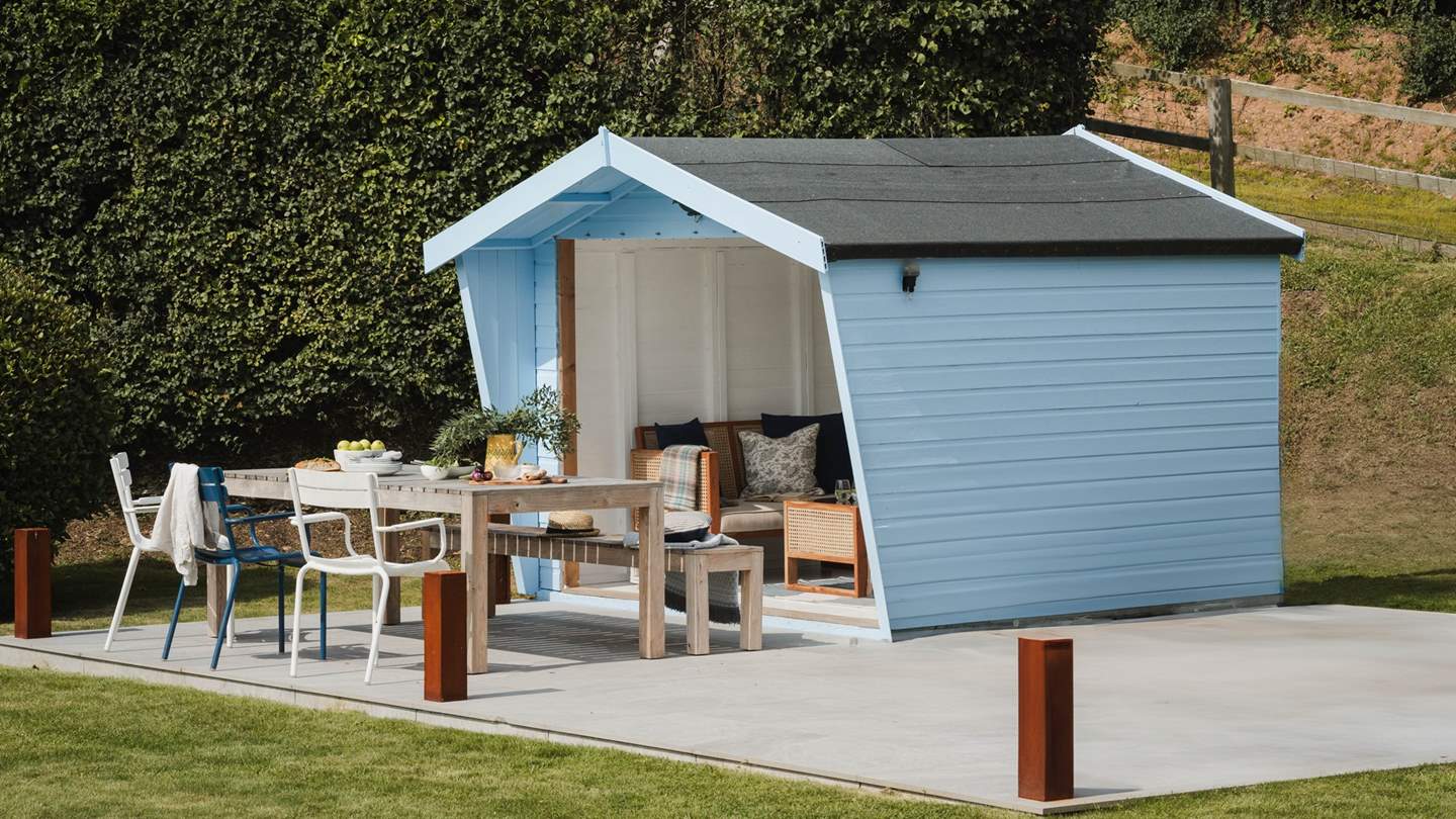 The garden features a well-kept lawn and a beautiful, duck egg blue summerhouse with an open-front aspect