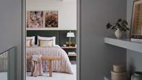 The master bedroom beckons with a sumptuous super king-size bed, framed by a statement headboard in deep forest hues 