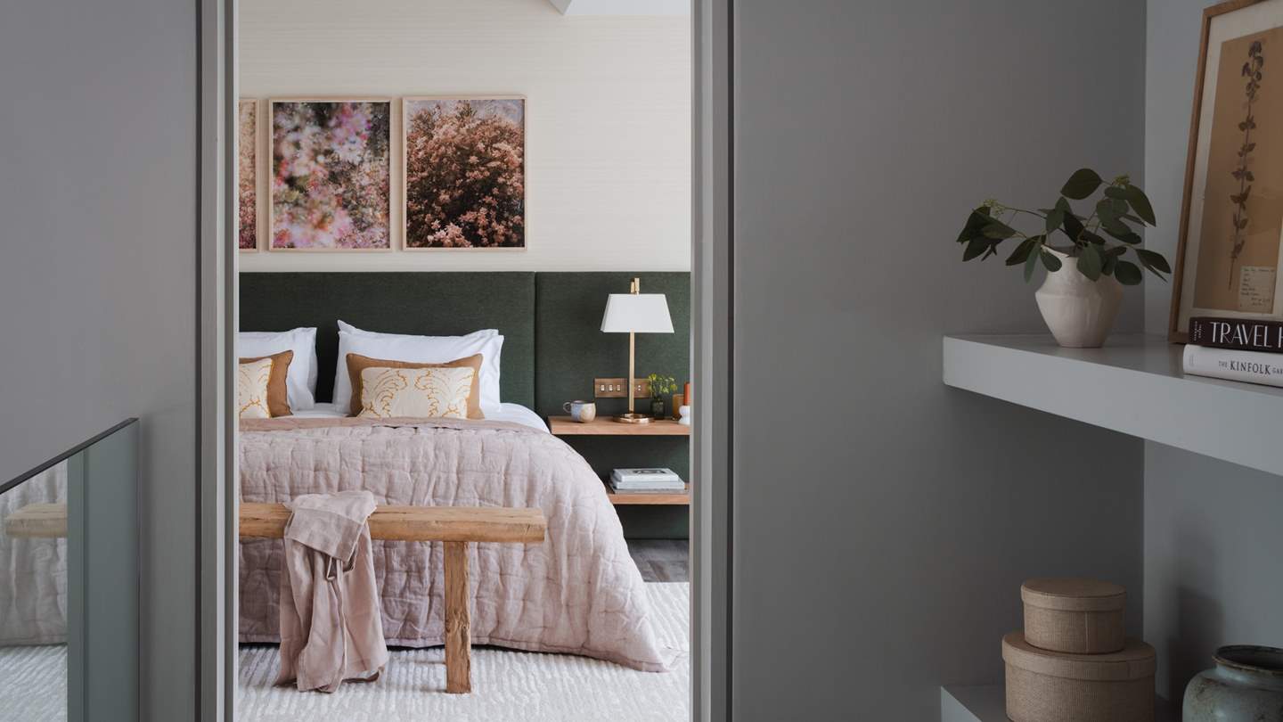 The master bedroom beckons with a sumptuous super king-size bed, framed by a statement headboard in deep forest hues 