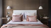 A king size bed takes pride of place, dressed in cushions and throws in soothing shades 