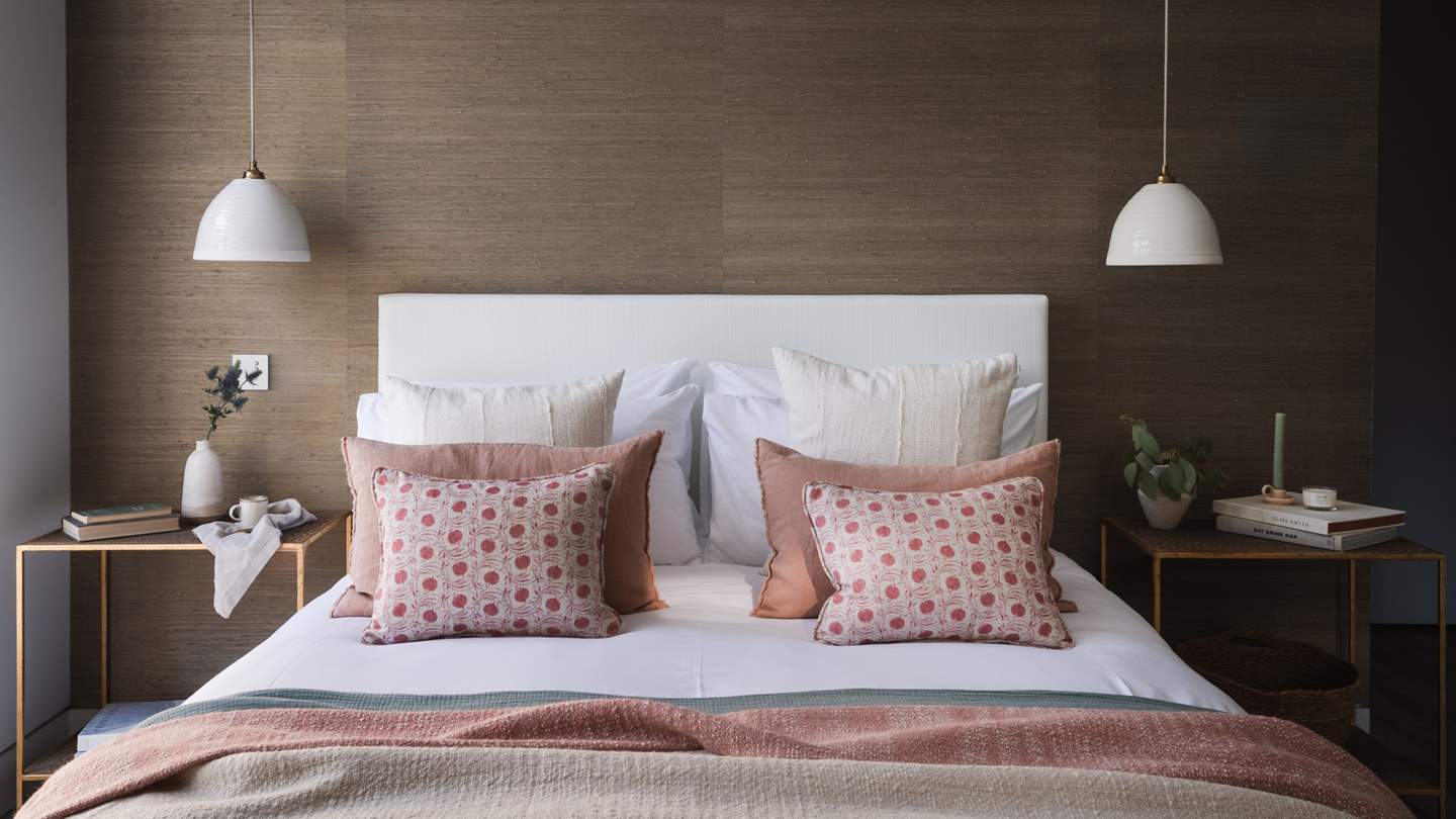 A king size bed takes pride of place, dressed in cushions and throws in soothing shades 