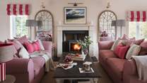 With two deep four-seater sofas in dusky rose arranged around a marble-topped coffee table, the sitting room beckons for relaxation 