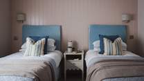 On the walls, painted wainscoting and walls imbue hygge vibes with pastel shades, elegantly paired with white linen and soft blue bed throws