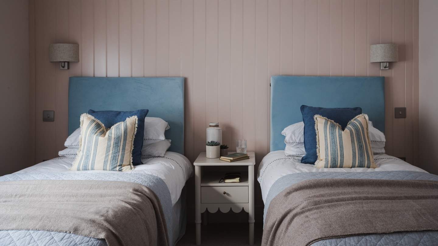 On the walls, painted wainscoting and walls imbue hygge vibes with pastel shades, elegantly paired with white linen and soft blue bed throws