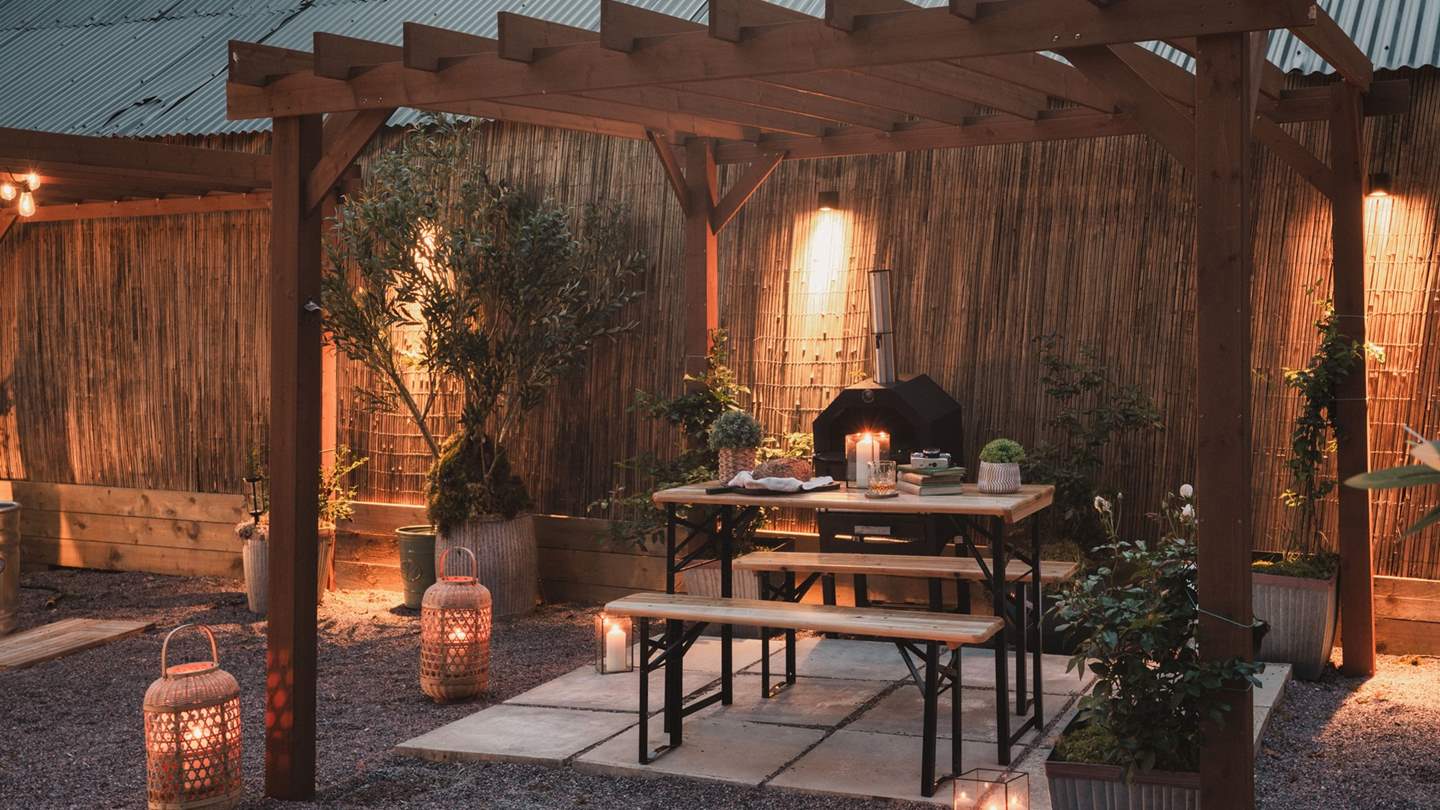 Festoon lighting illuminates this calming sanctuary, complete with a wood-fired pizza oven