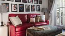 Exuding comfort, it features a vibrant red leather sofa and Persian footstool, as well as a sixty-five-inch Sky TV 