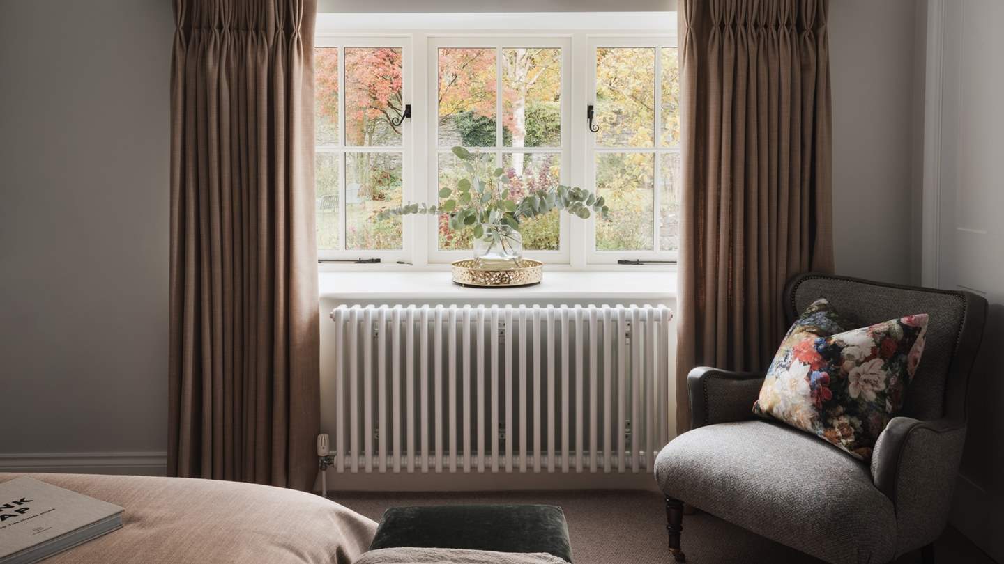Warm tones feature in a focal wall with statement wallpaper and overhead pendant lights, while sunshine cascades through large windows draped in full length curtains