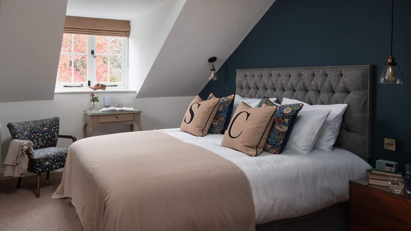Characterful sloping ceilings frame a picturesque alcove window in the eighth bedroom