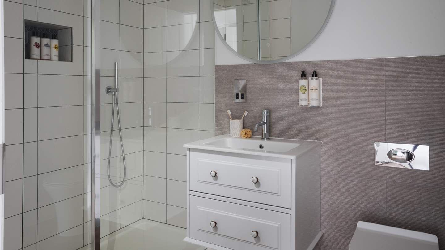 This bedroom features its own ensuite bathroom, complete with a shower designed with pearly white tiles