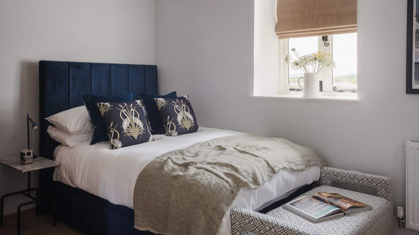 On the ground floor, a double bed is bedecked in the finest linens