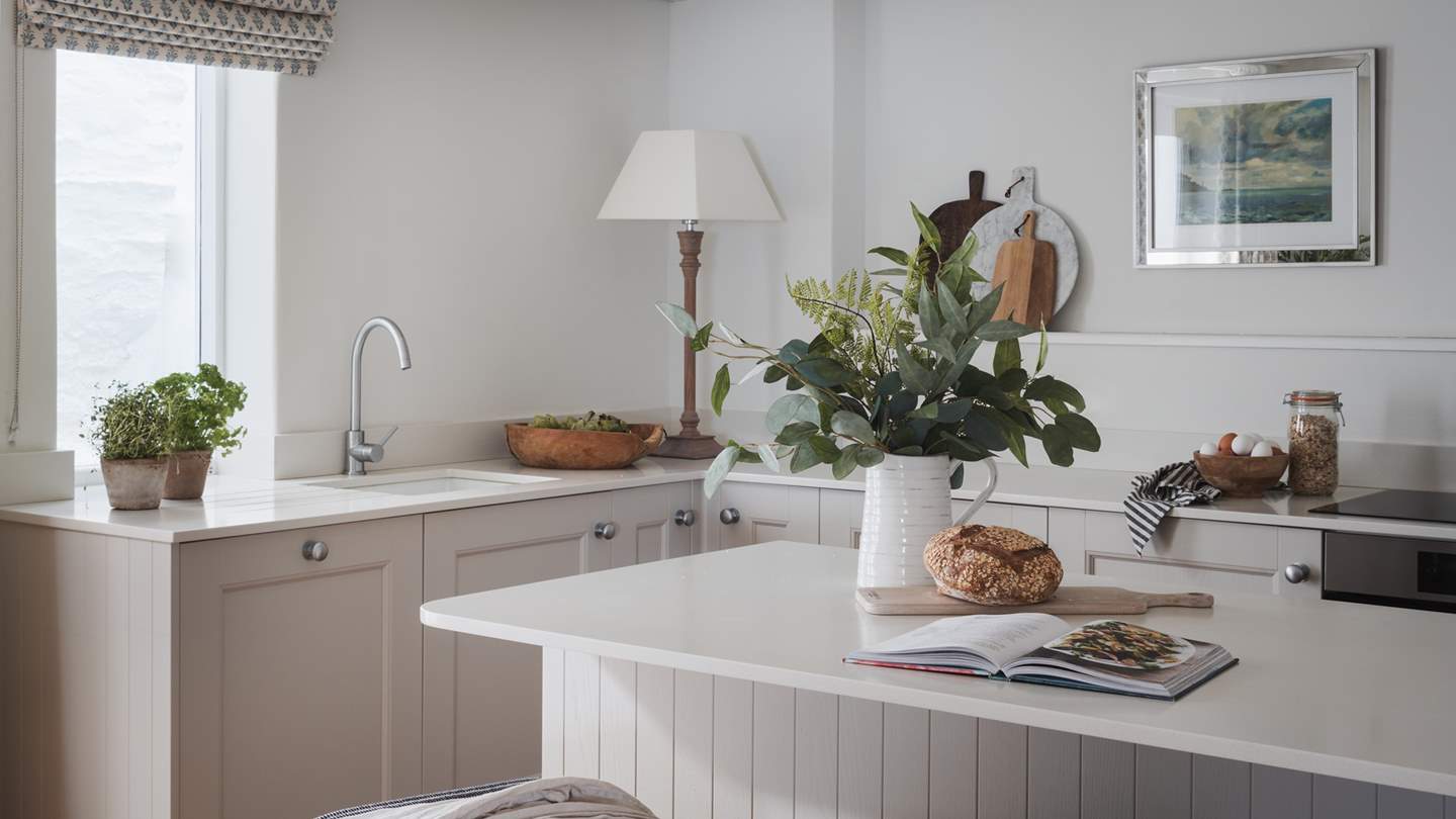 At the centre of the room, a painted kitchen island is paired with three breakfast stools for drawn-out mornings