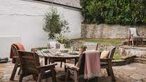 A peaceful suntrap sheltered by stone walls and manicured greenery, it is home to an outside table with seating for up to eight and two raised garden areas