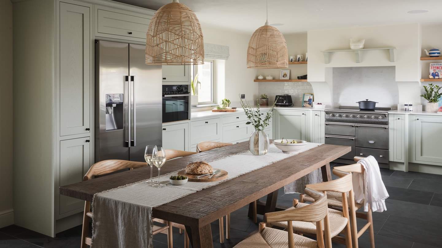 Dressed in subtle hints of sage and featuring white marble counter tops and open wood shelves, it imbues a timeless country cottage