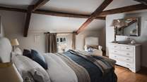 In the beautiful bedroom complete with charming, vaulted beams is an elegant sleigh-style king-sized bed