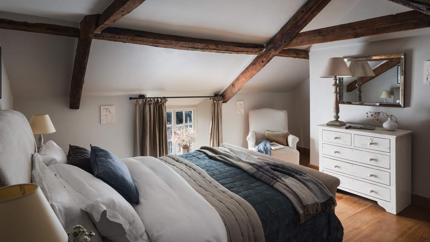 In the beautiful bedroom complete with charming, vaulted beams is an elegant sleigh-style king-sized bed