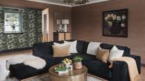 Inviting for movie night gatherings, you’ll find a black, L-shaped velvet sofa and a houndstooth armchair
